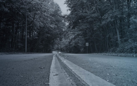 empty rural highway through forest with 25mph speed limit sign