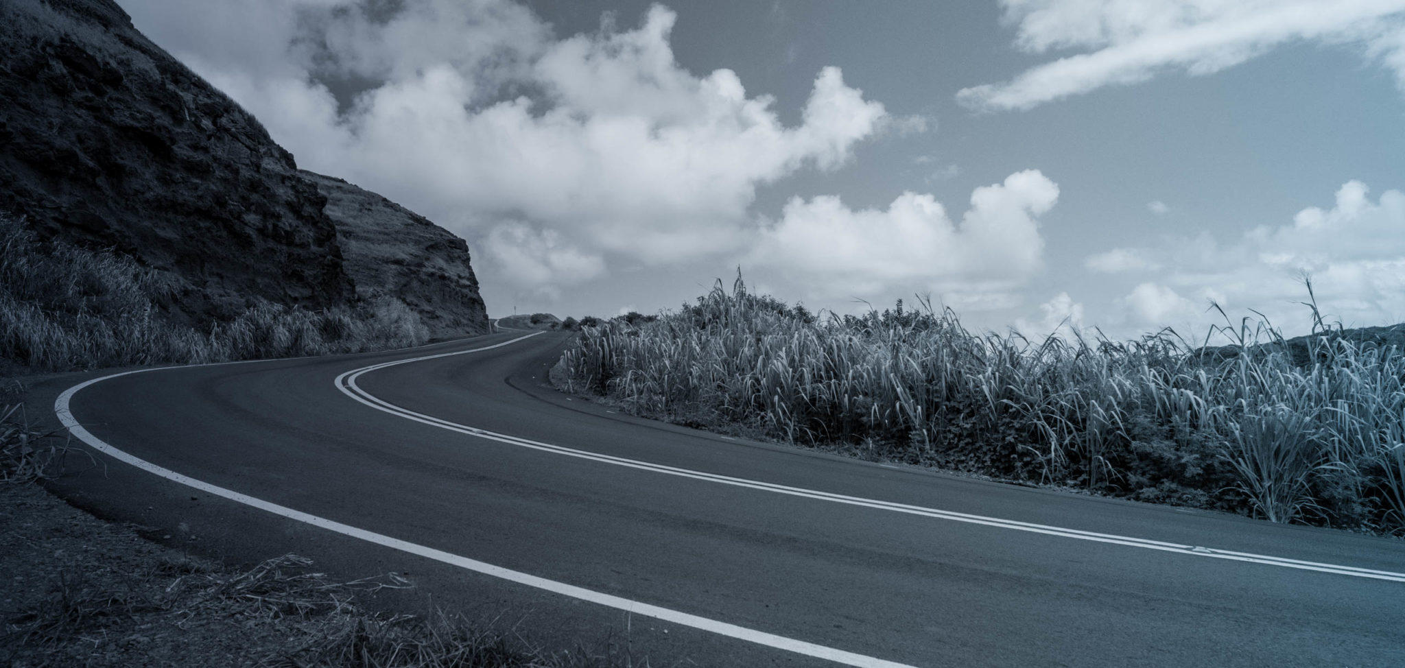 empty rural highway with long grass and hill