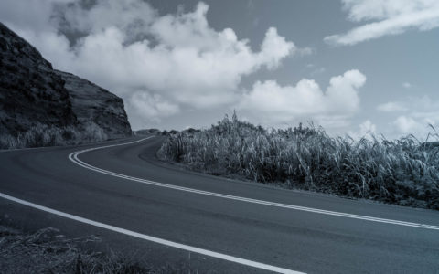 empty rural highway with long grass and hill